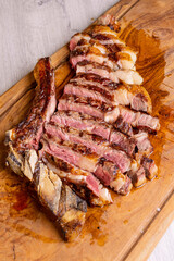 Bistecca di manzo cotta sulla brace, scaloppata e poggiata su un tagliere di legno in una braceria