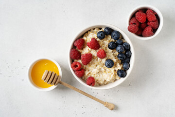 Porridge with berries, blueberry and raspberry in plate and honey