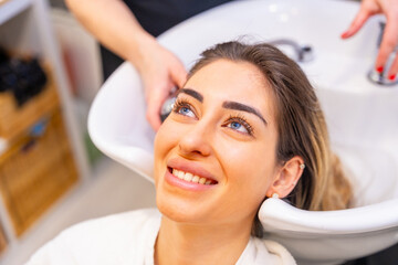 Client smiling while hairdresser wash her hair
