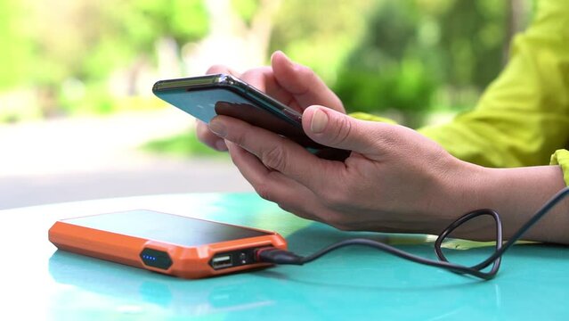 4k footage ogf Female hands using mobile phone while charging it with a portable power bank