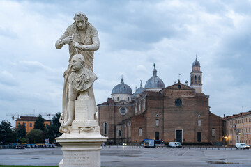 Marble statue of doctor perforating another man´s skull decorating public square in the italian city called Padova on a cloudy day
