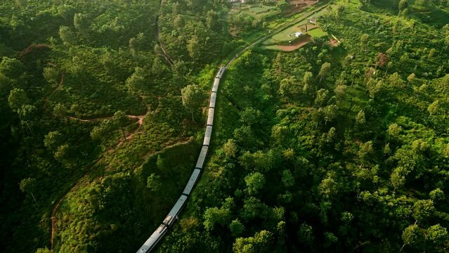 Train snakes through Haputale mountain landscape in Sri Lanka. Aerial drone railway amidst green tea plantations, terraces. Travelers experience rustic scenic beauty on iconic Ceylon journey.