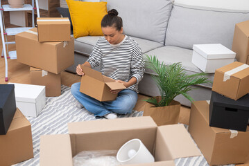Woman keeps box close to comfortable sofa in new modern house waiting for lovely husband from work...