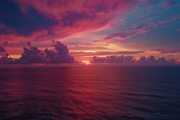 Aerial shot of a vibrant sunset over a vast ocean, with dramatic clouds ablaze with color