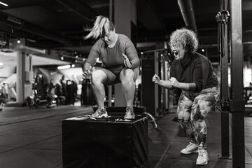 	
Two plus-size women embrace their bodies as they engage in a challenging workout. Doing squats at...
