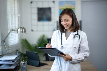 A woman doctor is writing on a clipboard in a room. She is smiling and seems to be happy
