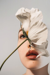 Artistic portrait of a woman with a white flower covering her face. Abstract minimal beauty concept.