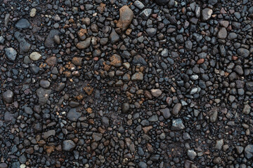 Texture of dark stones and black sand. Volcanic land, beach, natural pattern. Dark colors, small rocks.