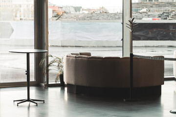 Sofa and coffee table in front of a large window. Waiting room, atrium of a large building.