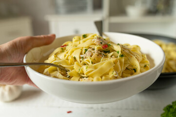 Plate with pasta aglio e olio and chicken breast. Healthy homemade food serving by woman´s hands