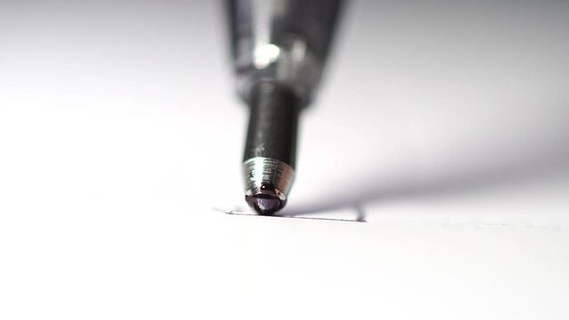 A ballpoint pen writes. Close-up of the ball spinning.