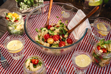 Veganer Italienischer Nudelsalat draußen auf dem Tisch rot weis karierte Tischdecke