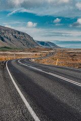 Long asphalt road runs through Iceland. Travelling, exploring, breathtaking views, volcanic landscapes.