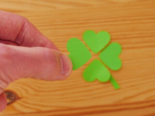 A hand holding a green paper heart with the word clover on it
