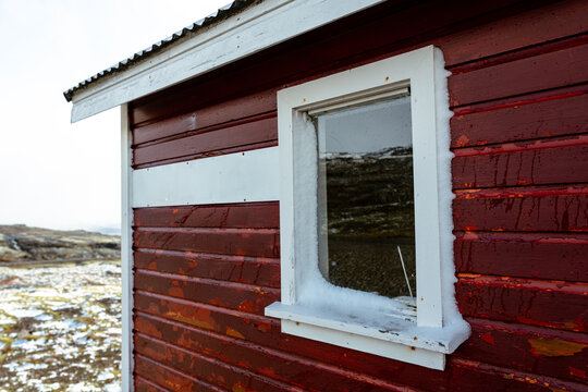 White window on red wooden wall. Small refuge in the mountains. Winter, snow, high altitudes.