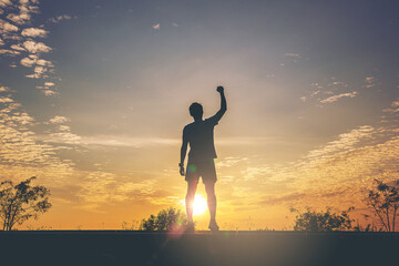 Silhouette of man runner standing and open arm celebrate his success with healthy at the road track...