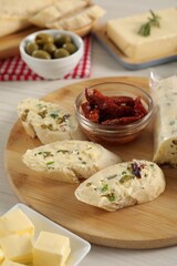 Tasty bread with butter, green onion, chili peppers and olives on wooden table