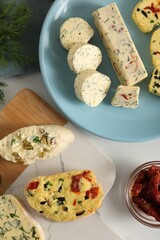 Different types of tasty butter, dill, chili peppers and bread on white table, flat lay