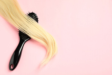 Stylish brush with blonde hair strand on pink background, top view. Space for text