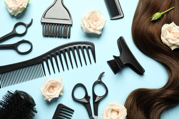 Flat lay composition with professional hairdresser tools, flowers and brown hair strand on light...