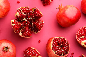 Whole and cut fresh pomegranates on pink background, flat lay