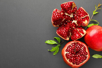 Fresh ripe pomegranates and leaves on grey background, top view. Space for text