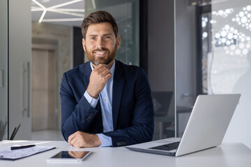 Confident businessman smiling at desk with laptop