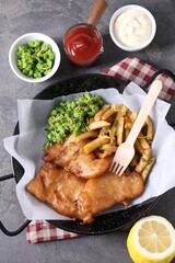 Tasty fish, chips, sauces and peas on grey table, flat lay