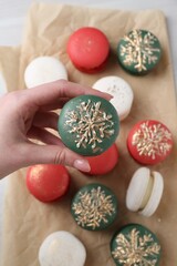 Woman with decorated Christmas macaron at table, top view