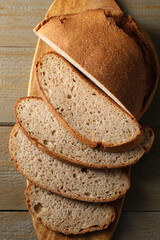 Freshly baked cut sourdough bread on wooden table, top view