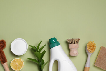 Flat lay composition with different cleaning supplies on green background, space for text