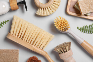 Cleaning brushes, soap, dispenser and fern leaves on grey background, flat lay