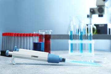 Laboratory analysis. Micropipette, petri dish, beakers and test tubes on light grey table