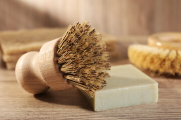 Cleaning brush and soap bar on wooden table, closeup