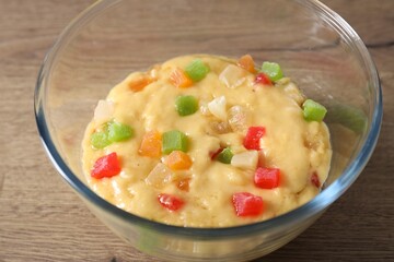 Raw dough with candied fruits in bowl on wooden table, closeup
