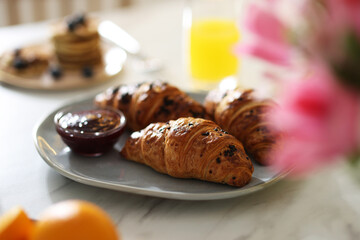 Tasty breakfast. Plate with fresh croissants and jam on white marble table, closeup