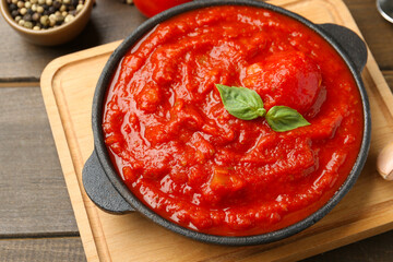 Homemade tomato sauce and basil in bowl on wooden table