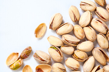 Pistachios scattered on plain white surface with copy space