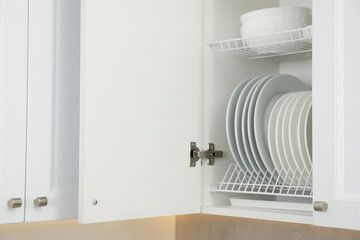 Clean plates and bowls on shelves in cabinet indoors