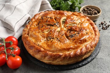 Tasty homemade pie, spices and fresh tomatoes on grey table