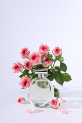 Bottle of luxury perfume and beautiful roses on white background. Floral fragrance