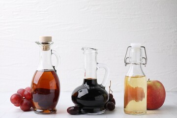 Different types of vinegar and ingredients on light tiled table, closeup