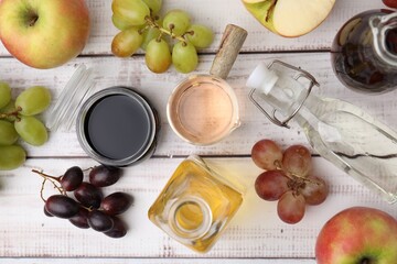 Different types of vinegar and ingredients on wooden table, flat lay