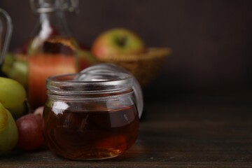 Vinegar in glass jar and grapes on wooden table, space for text