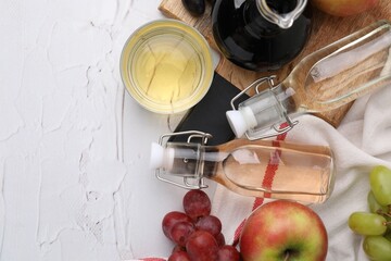Different types of vinegar and fresh fruits on white table, top view. Space for text