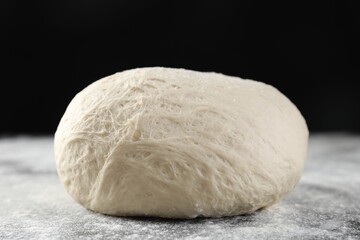 Raw homemade dough and flour on black table