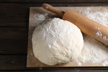 Raw dough and rolling pin on wooden table, above view