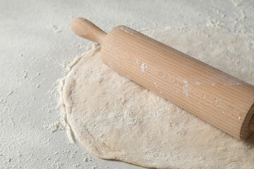 Raw dough and rolling pin on table