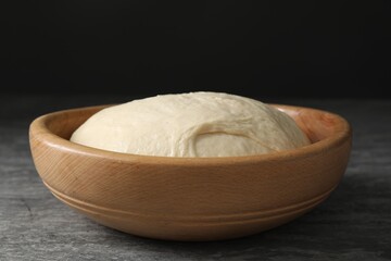 Raw dough in bowl on grey table