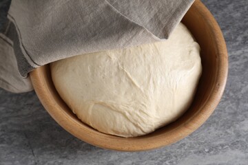 Raw dough in bowl on grey table, top view